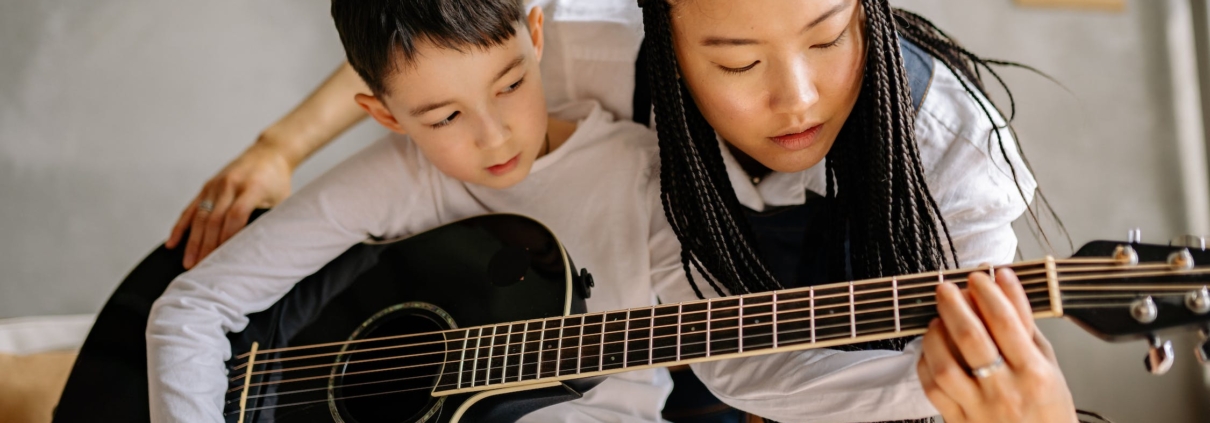 Mom teaching son how to play guitar