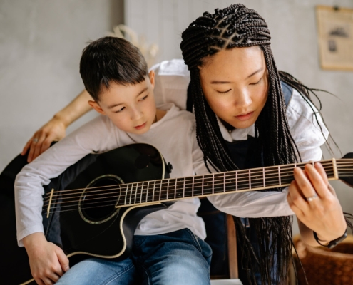 Mom teaching son how to play guitar