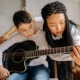 Mom teaching son how to play guitar