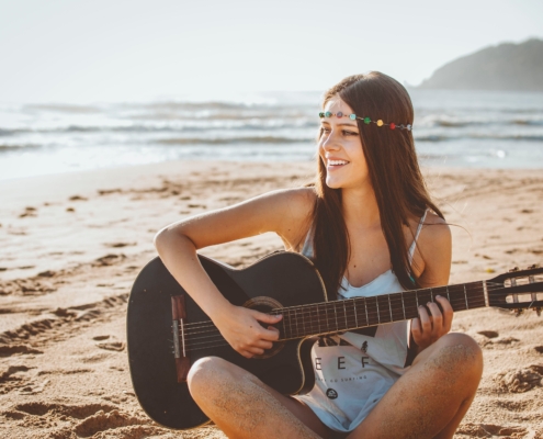 smiling hippie girl playing guitar